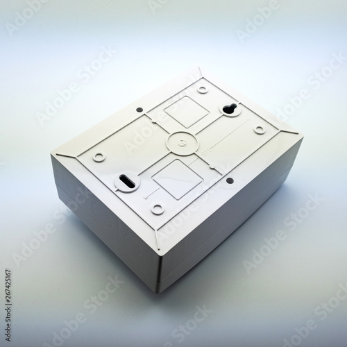 Plastic gray plastic electrical installation junction box on a white background. Electric switchboard on the white wall of a factory.