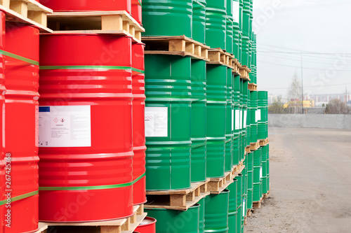 Barrels of 200 liters of metal are in the pallet on the street. Red and green barrels for petroleum, chemicals, gasoline. Close-up.