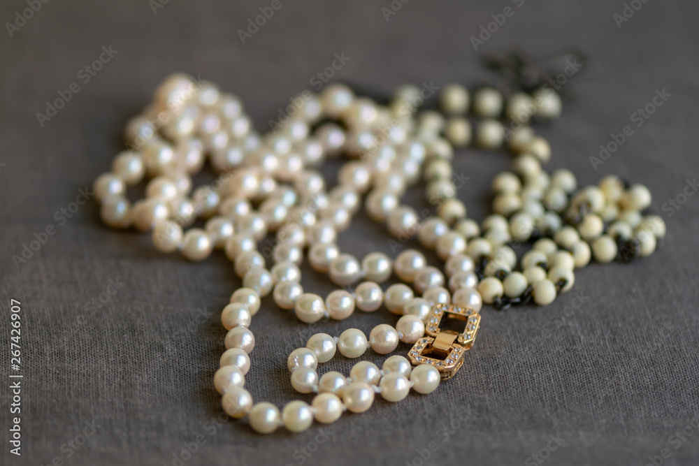 White rosary and pearl necklace on linen fabric. Luxury and modesty. White rosary and pearl necklace on linen fabric. Luxury and modesty.