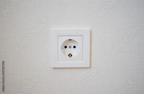 White wall outlet on grey plaster European interior outlet socket. Daylight.