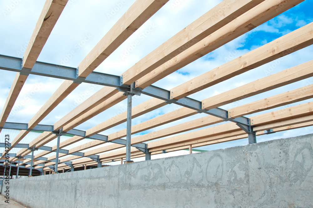 Wooden beams and metal frame of the new building. The use of two materials in construction. Wood and metal at a construction site.