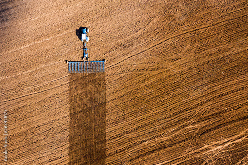 Spring agricultural work in the fields. Plowing and harrowing the soil with a tractor. The view from the top. Copy space. Concept: Timely preparation of soil for sowing is the key to a good harvest.