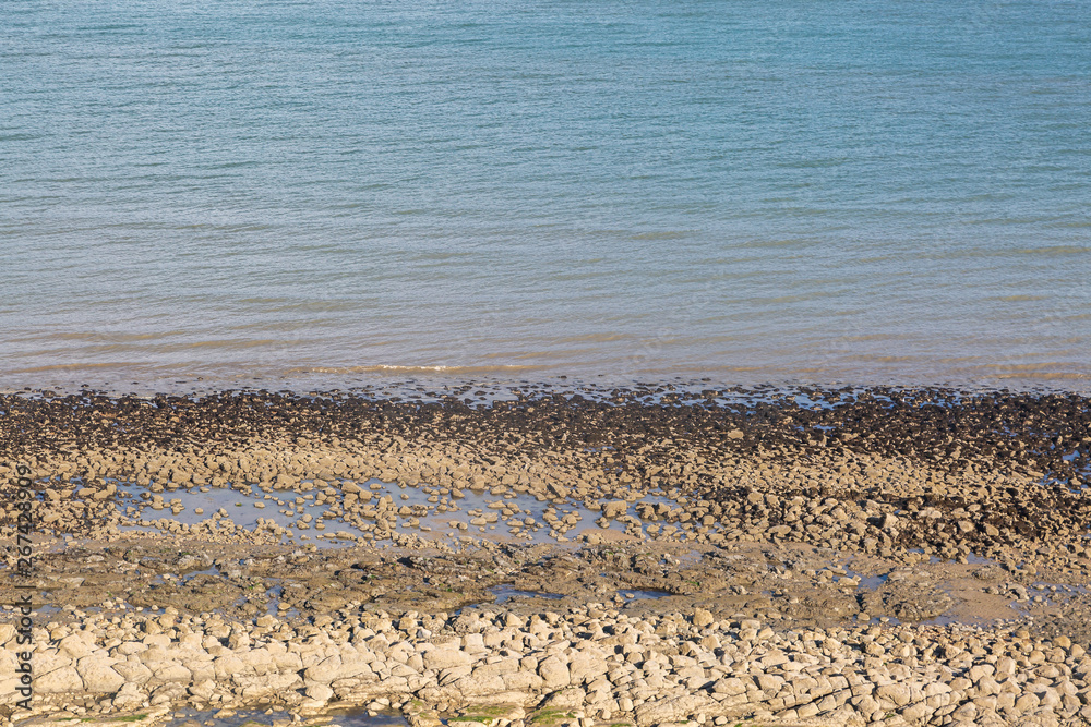 Looking down at pebbles and the sea, at low tide Looking down at pebbles and the sea, at low tide