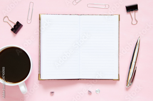  Workspace with notebook  stationery supplies and cup of coffee on pink background. Top view with copy space.