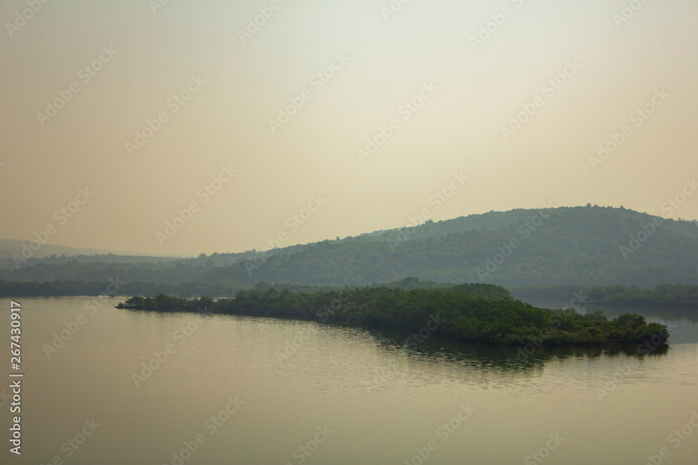 small island with green trees against the backdrop of a misty river valley