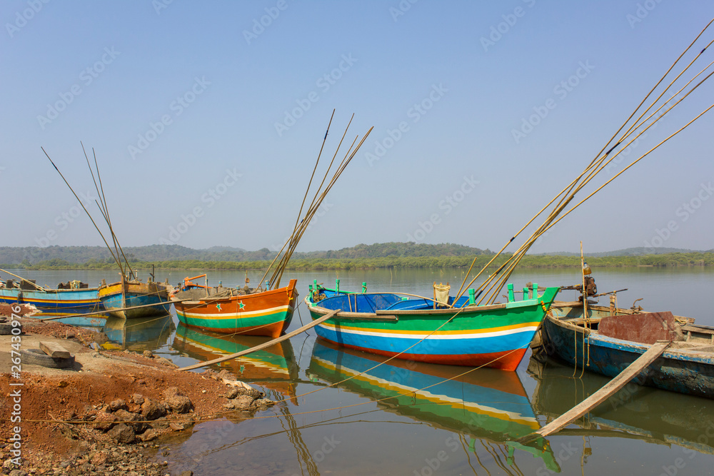 new colorful Indian boats with fishing rods anchored off the coast against the backdrop of the river