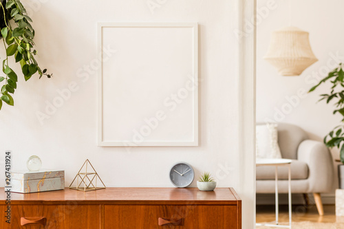 Stylish and retro space of home interior with white mock up frame, design sofa, furnitures, vintage cupboard with elegant accessories, plants and coffe table. Cozy home decor. Minimalistic concept. © FollowTheFlow