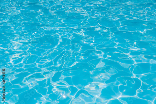 Pattern of blue water surface in swimming pool, Ripple wave and motion water for blue background and abstract, Bright and purified water with sun reflection in pool