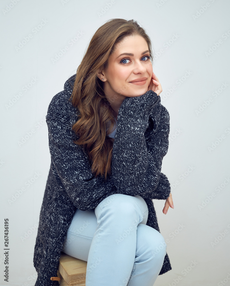 Woman dressed in knitted sweater sitting on stool. Woman dressed in knitted sweater sitting on stool.