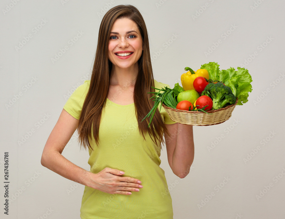 woman holding big plate with vegetables and salad leaves holds hand on belly. woman holding big plate with vegetables and salad leaves holds hand on belly.