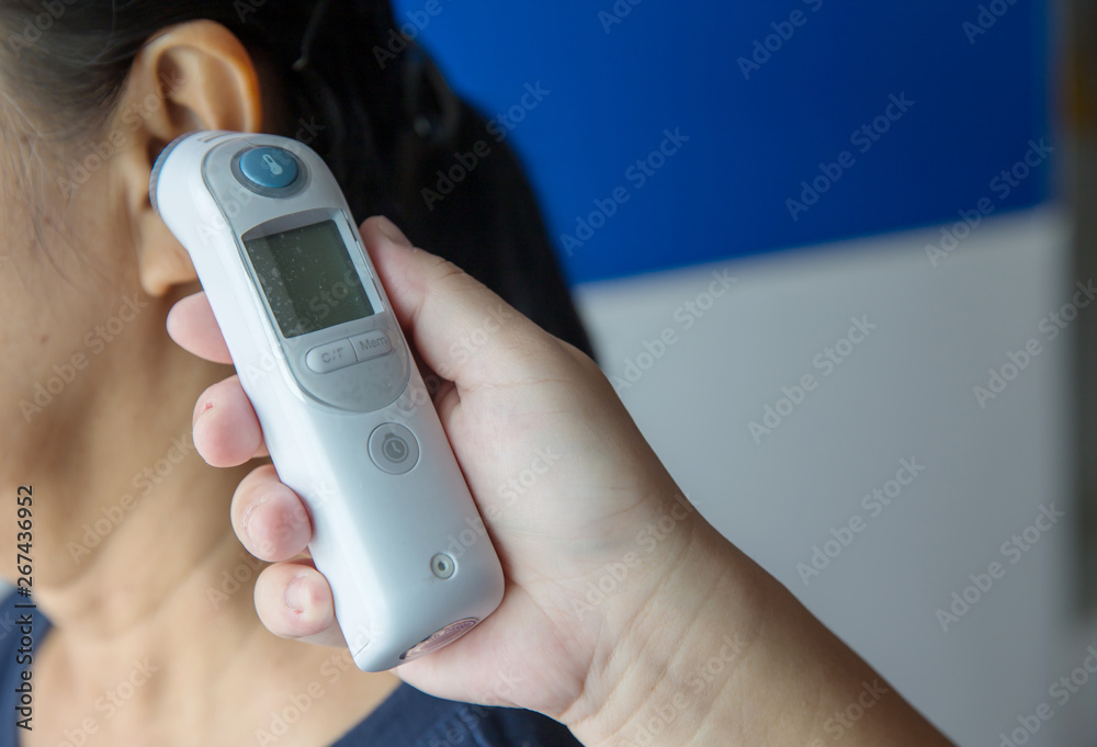 Doctor checking patient's temperature in the ear with Tympanic