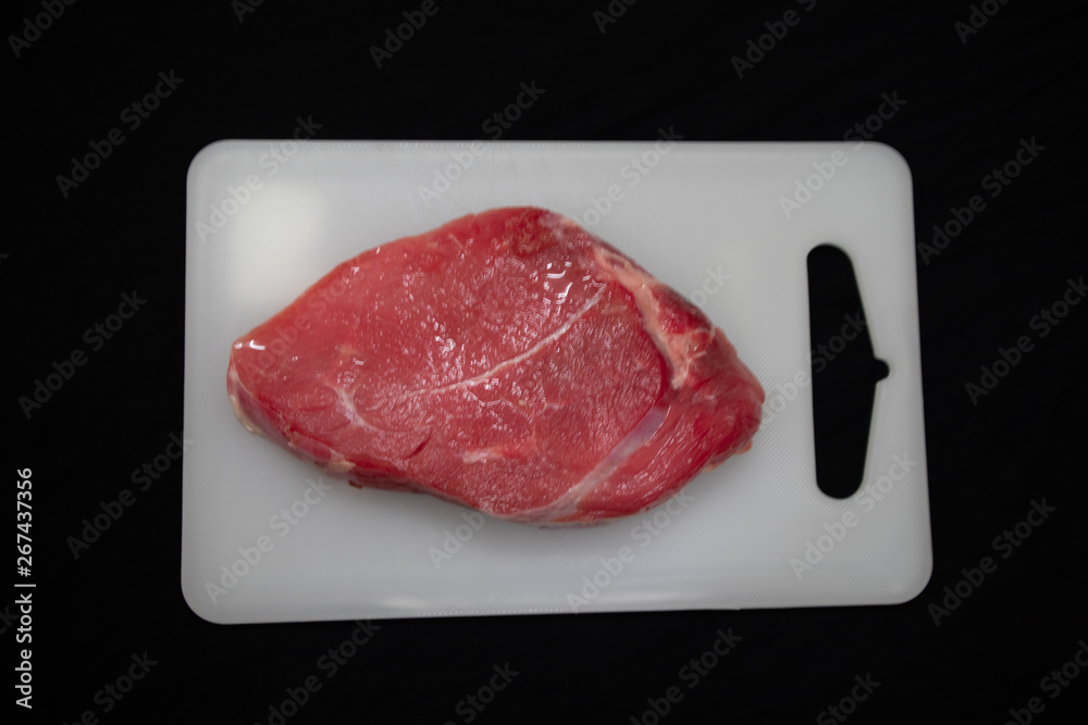 Fresh red meat is placed on the cutting board to prepare to cook. Fresh red meat is placed on the cutting board to prepare to cook.