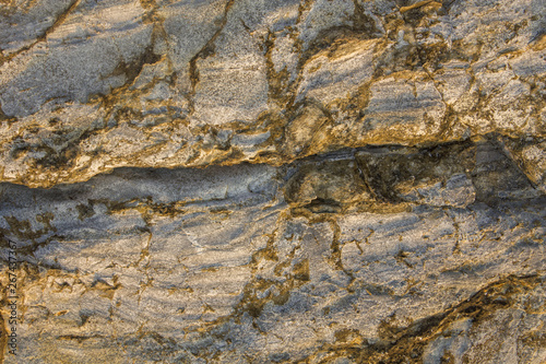 gray yellow rock with very deep relief, cracks and shadows. natural surface texture