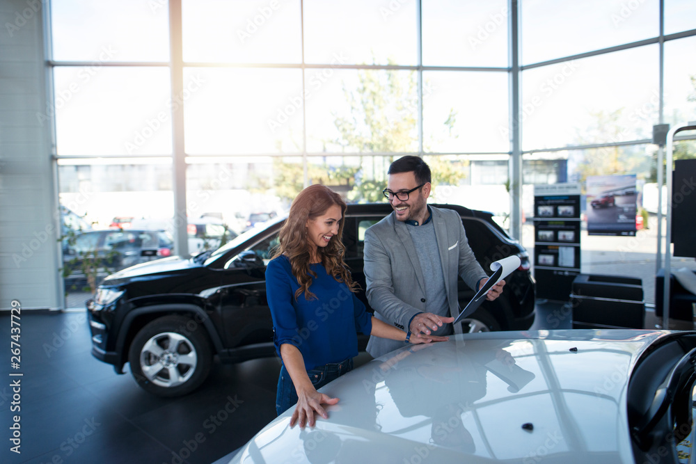 Car dealer presenting new vehicle to the customer. Brand new vehicles. Automobile dealership.