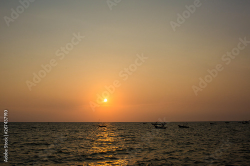 Bright sunset with large yellow sun under the sea surface. sunrise in the sea. Beautiful sunset above the sea. Tropical sunset on the beach.