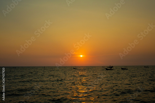 Bright sunset with large yellow sun under the sea surface. sunrise in the sea. Beautiful sunset above the sea. Tropical sunset on the beach. © kanpisut