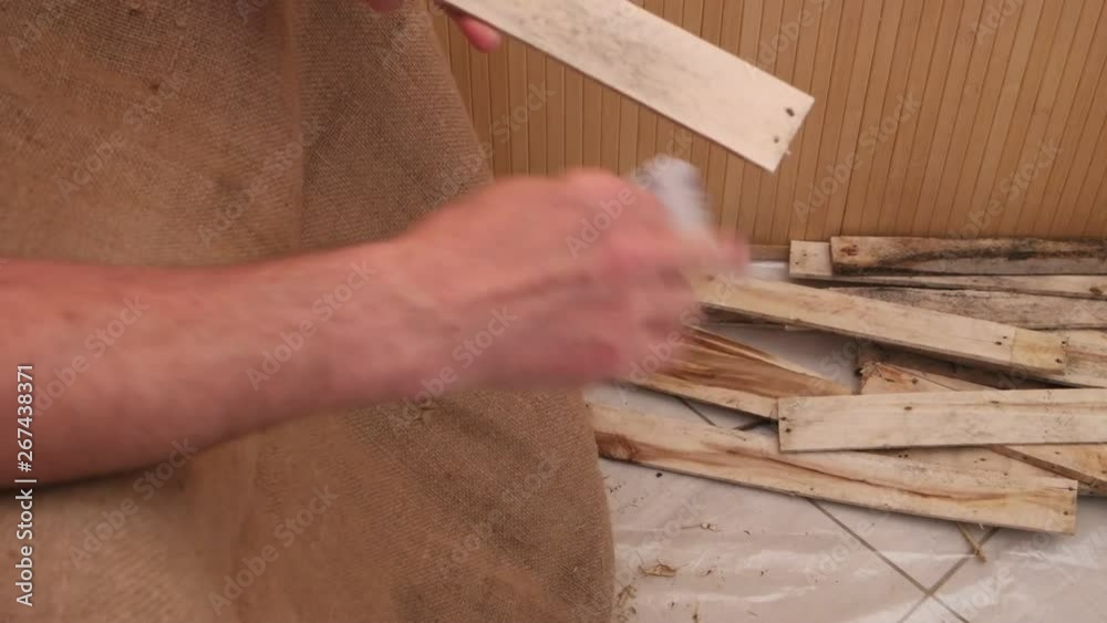 A man grinds wooden planks from the old box with an abrasive disc by hand at home A man grinds wooden planks from the old box with an abrasive disc by hand at home