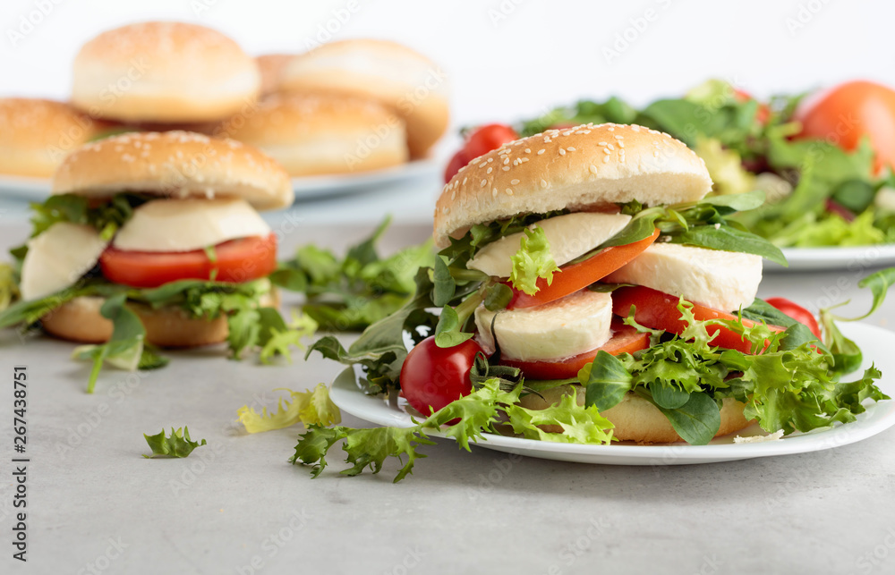Sandwich with mozzarella, tomato and salad on the kitchen table.