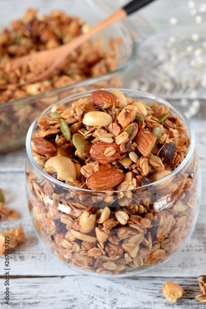 Obraz premium Granola with different nuts in a glass jar on the white wooden table
