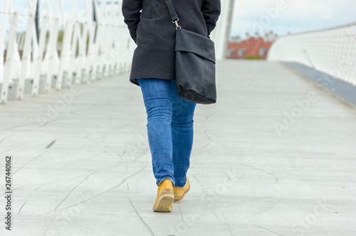 Woman wearing jeans and handbag walking away © michaelheim