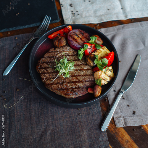 Beef steak with a side dish of grilled vegetables, with natural light from the window on a wooden table, BBQ
