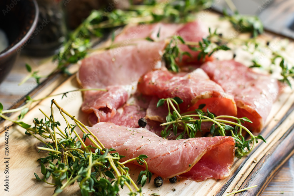 Delicious flavorful ham sliced into strips on a wooden background with spices and fresh thyme. A serving of low-fat succulent farm meat pork. meat product. Food Photography Delicious flavorful ham sliced into strips on a wooden background with spices and fresh thyme. A serving of low-fat succulent farm meat pork. meat product. Food Photography