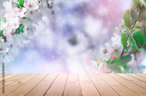 Empty wooden table  natural delicate flowers in the background  sun rays. Light delicate floral background pattern