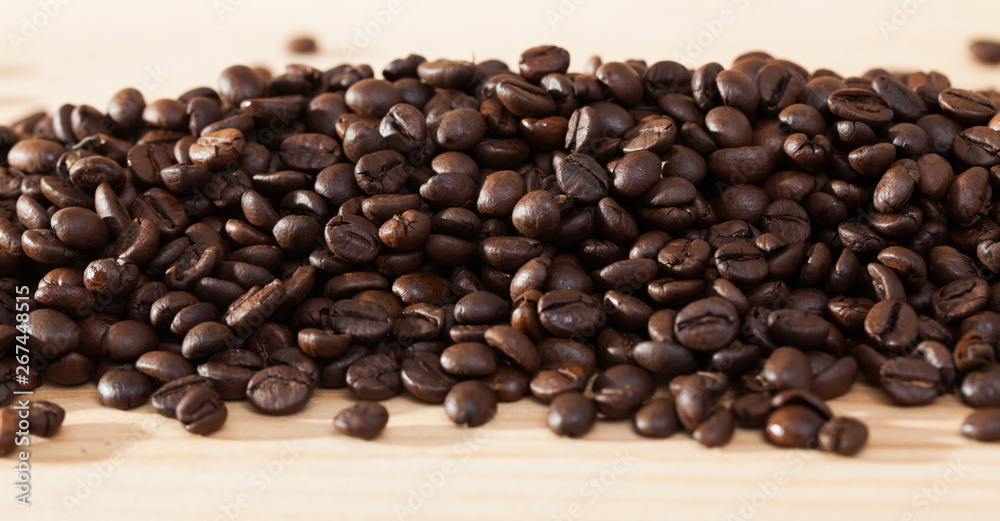 Fototapeta premium Coffee beans on light wood surface