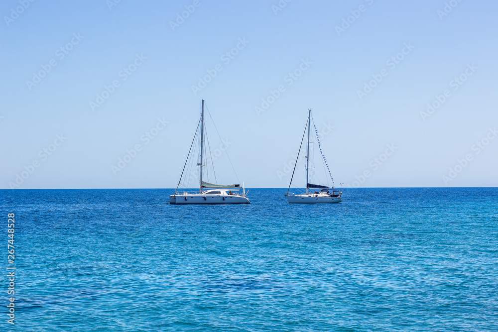 yachts on calm vivid blue water surface of Mediterranean sea near south Greece coast, cruise and summer rest picture in clear weather time, copy space 