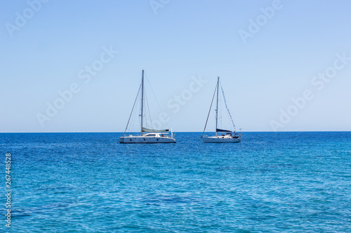 yachts on calm vivid blue water surface of Mediterranean sea near south Greece coast, cruise and summer rest picture in clear weather time, copy space 