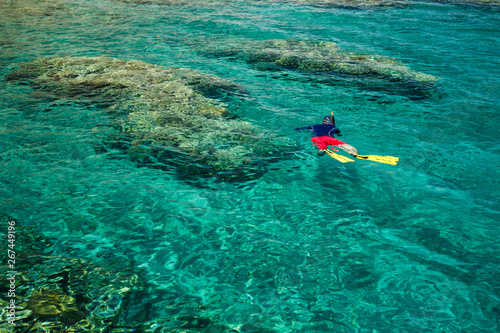 guy snorkeling with elementary equipment mask tube and flippers and enjoy beautiful coral bottom of the Red sea Middle East resort ecology nature space for vacation and rest, copy space