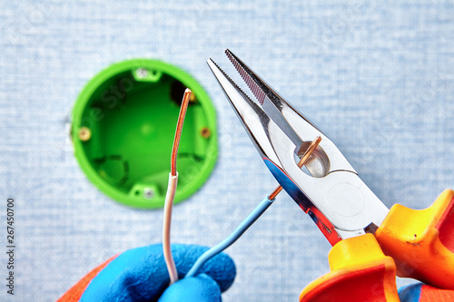 Installation of round electrical box with pliers. photo