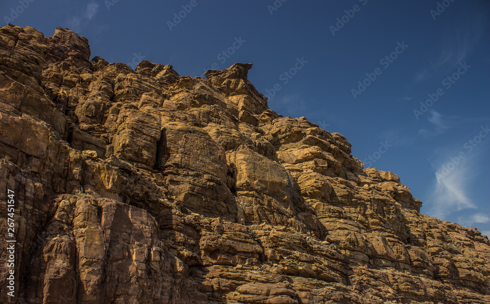 sand stone mountain rock from below on saturated blue sky background in desert 