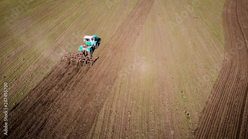 Farmer on tractor with plow cultivating arable land for seeding crops. Spring agricultural activities with heavy machinery photo