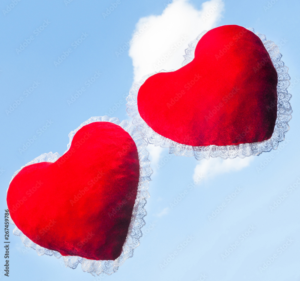 Fototapeta premium Two red heart shaped cushions against the sky