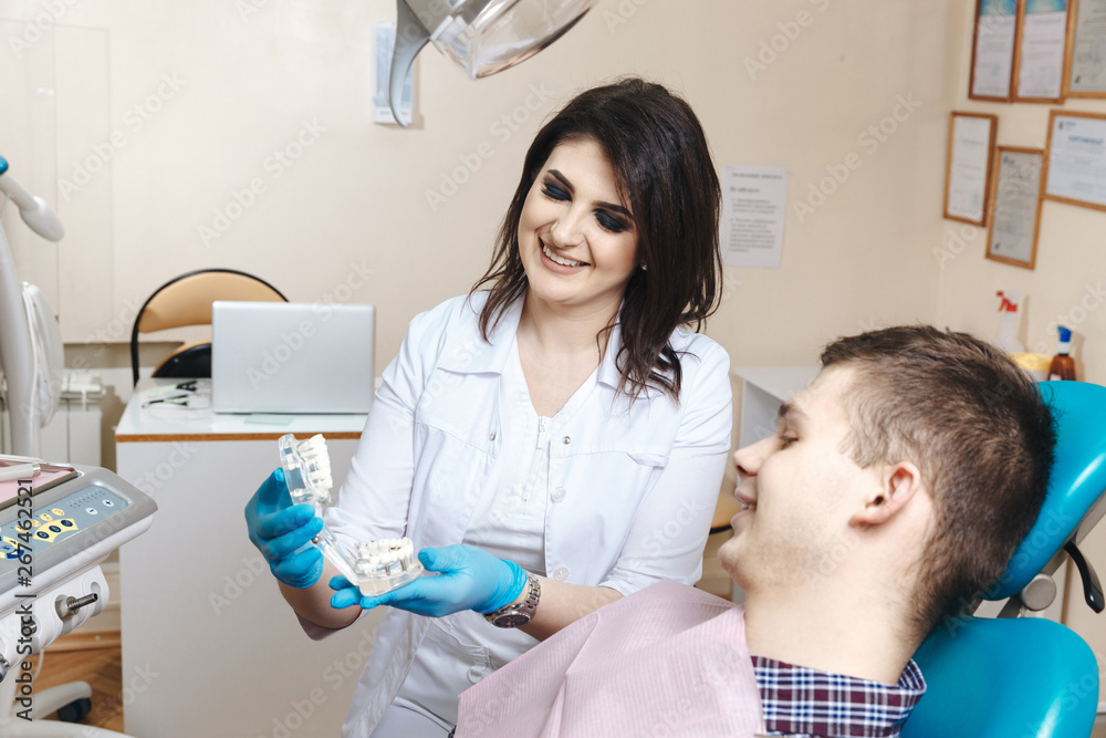 Dentist showing denture to the male patient Dentist showing denture to the male patient