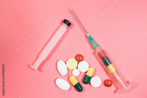 Syringe and pill on pink background - medicine concept. Syringe, needle and pills.  © FATIR29