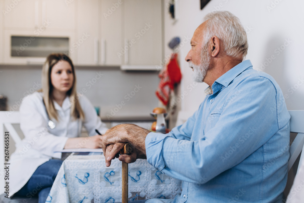 Young positive caregiver taking care of senior man in nursing home Young positive caregiver taking care of senior man in nursing home