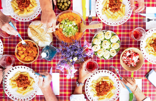 Above view of four caucasian people enjoying brunch together. Table with checkered tablecloth. Pasta, eggs and vegetables