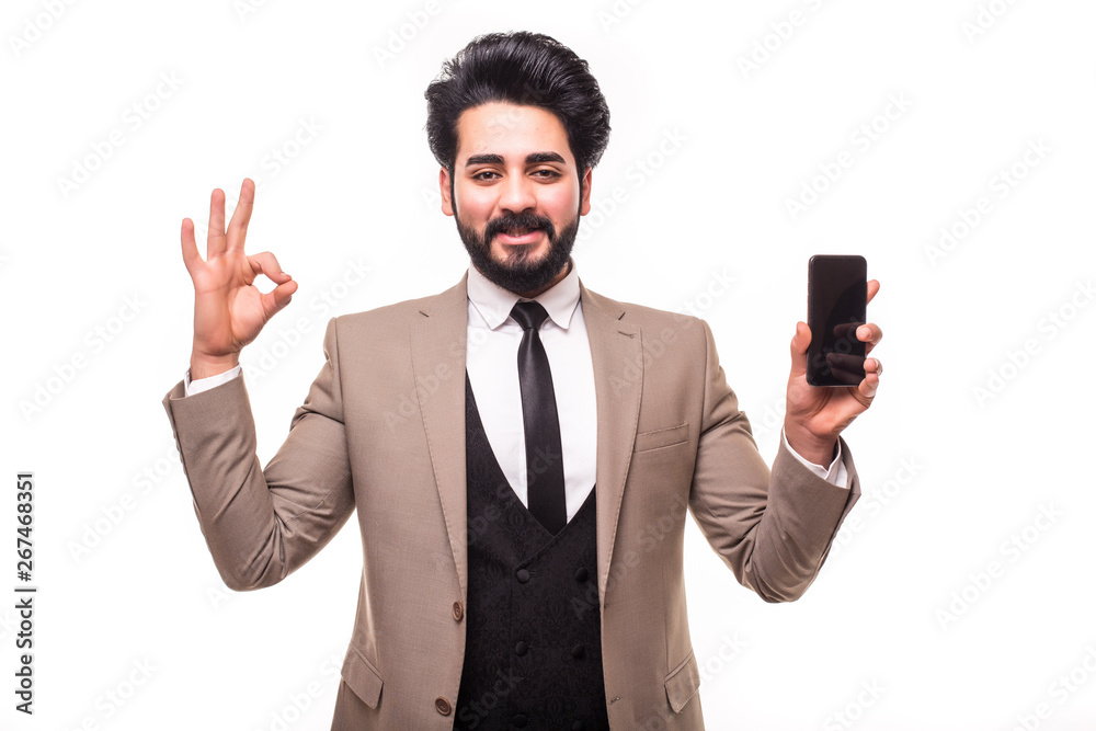 Portrait of arab handsome business man posing holding mobile phone showing okay gesture isolated over white background Portrait of arab handsome business man posing holding mobile phone showing okay gesture isolated over white background