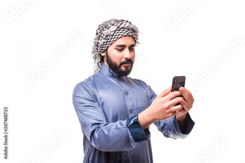 Young arab man wearing in traditional abaya clothes with phone isolated on white background © F8  \ Suport Ukraine