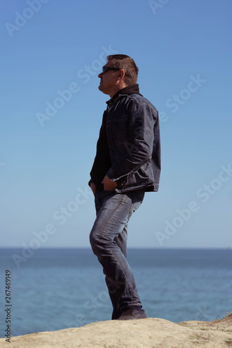 A man in a denim suit on the background of the sea in a spring sunny day. © Виктор Кеталь