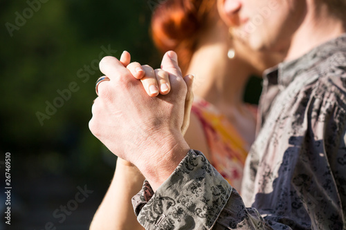 closeup shot of the hands of two young people dancing tango outside