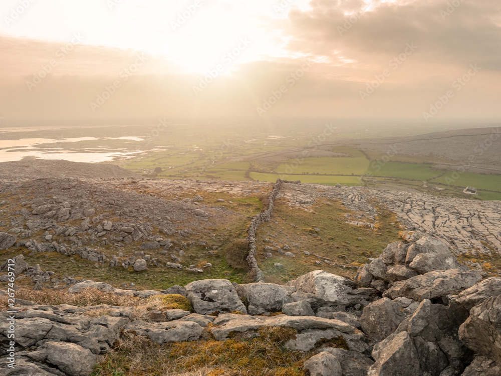 The sun shines over Burren national park, county Clare, Ireland, cloudy day, sun flare,