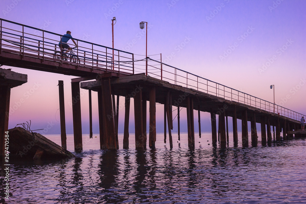 cyclist rides to the pier during sunset