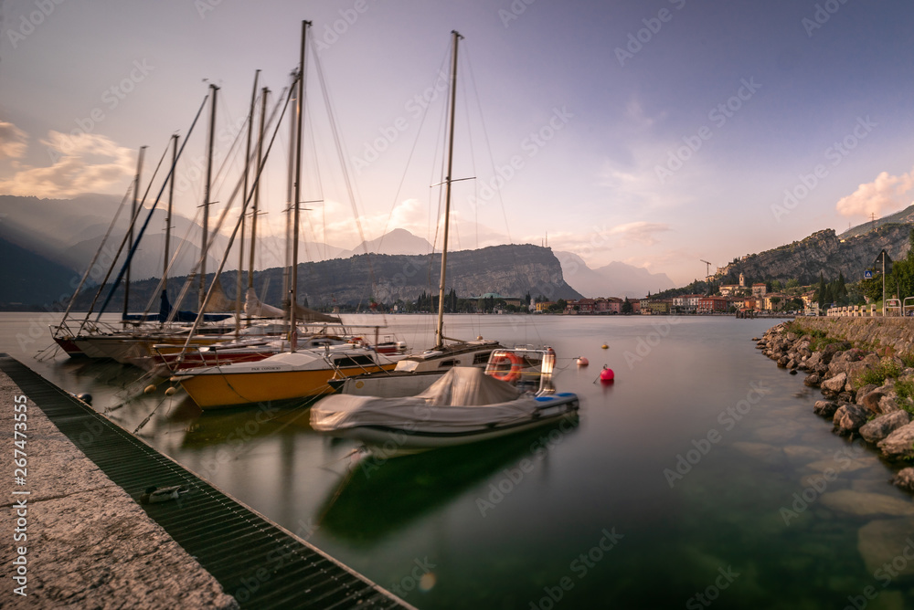 Fototapeta premium Sailing, boats, in a harbor. Lago di garda, garda lake, torbole, boat on a lake in the evening sun. calm, chill, faded water