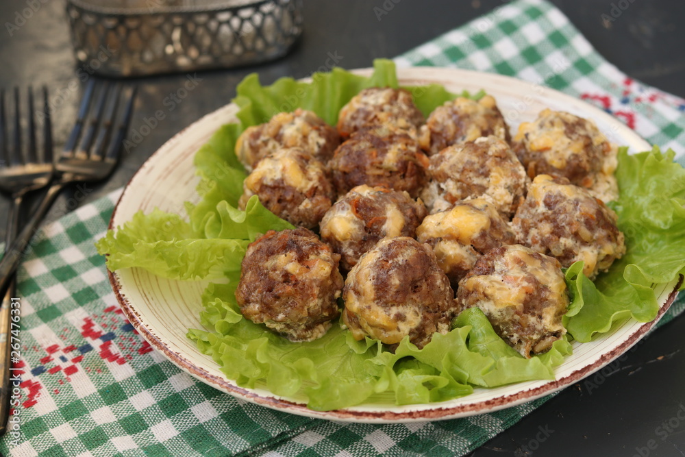 Meatballs in a sauce of cheese and sour cream are located in a plate on a dark background Meatballs in a sauce of cheese and sour cream are located in a plate on a dark background