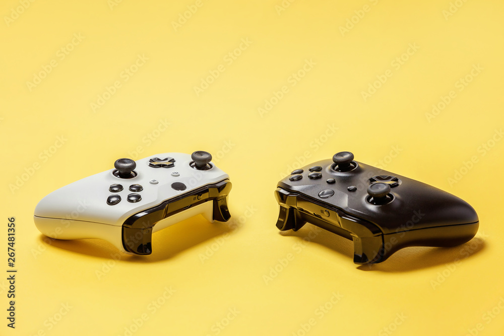White and black two joystick gamepad, game console on yellow colourful trendy modern fashion pin-up background. Computer gaming competition videogame control confrontation concept. Cyberspace symbol