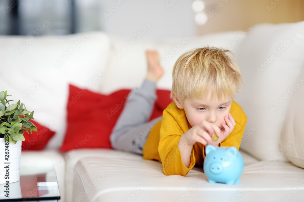 Little boy putting coin into piggy bank. Little boy putting coin into piggy bank.