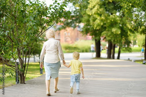 Beautiful granny and her little grandchild walking together in park. © Maria Sbytova